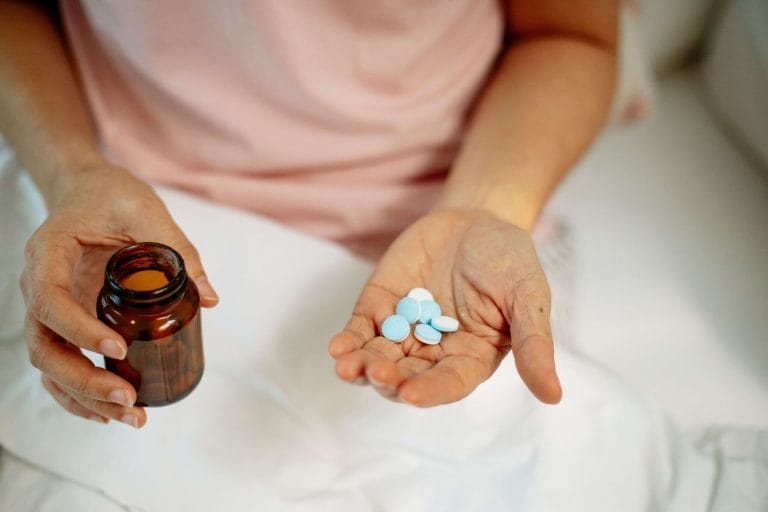 Person håller glycintabletter i handen bredvid en öppnad burk