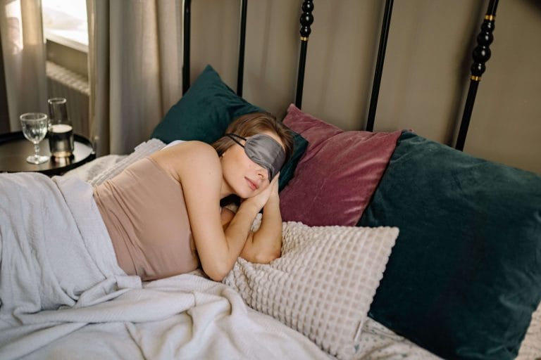 Kvinna som sover med ögonmask i sängen