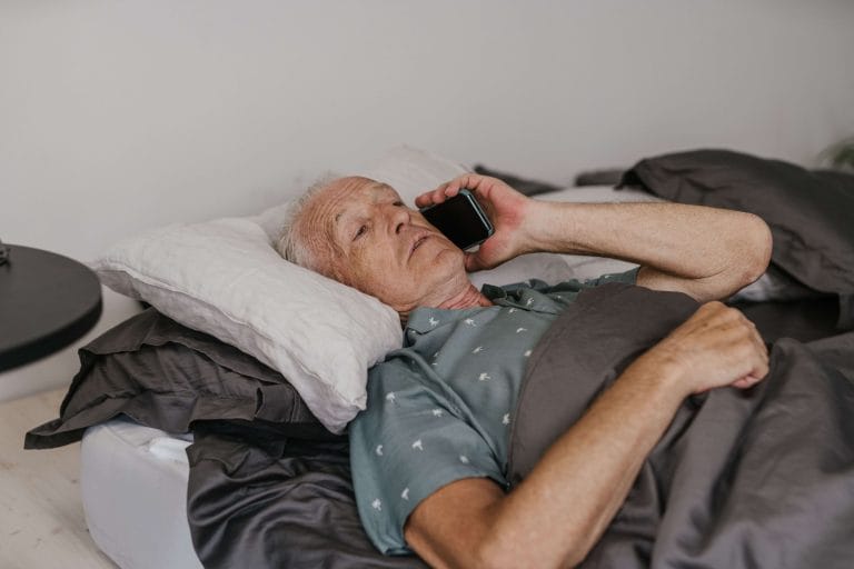Man ligger i sängen och pratar i telefon