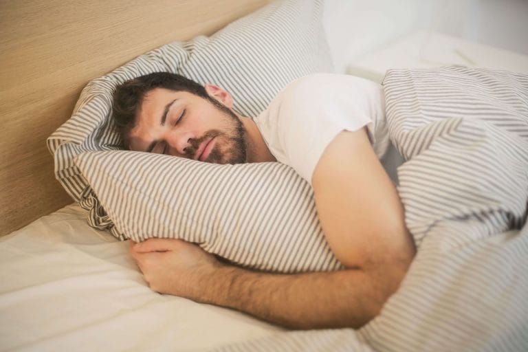 Man sover med armarna om en kudde