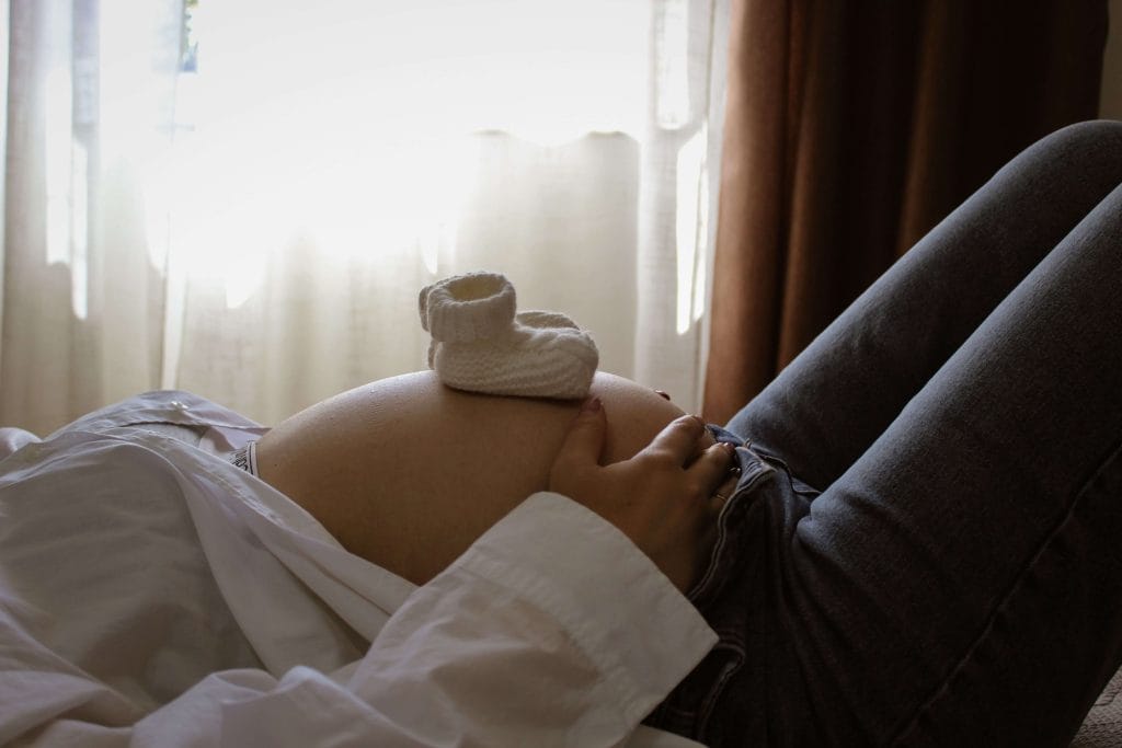 Gravid kvinna ligger på rygg i sängen