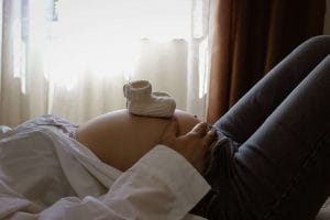 Gravid kvinna ligger på rygg i sängen