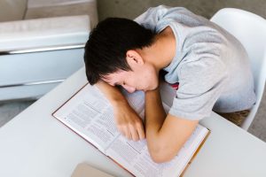 Ung man med ADHD och sömnproblem har somnat med huvudet på en uppslagen bok