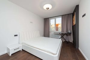 Bäddad säng med vitt överkast i ett ljust sovrum