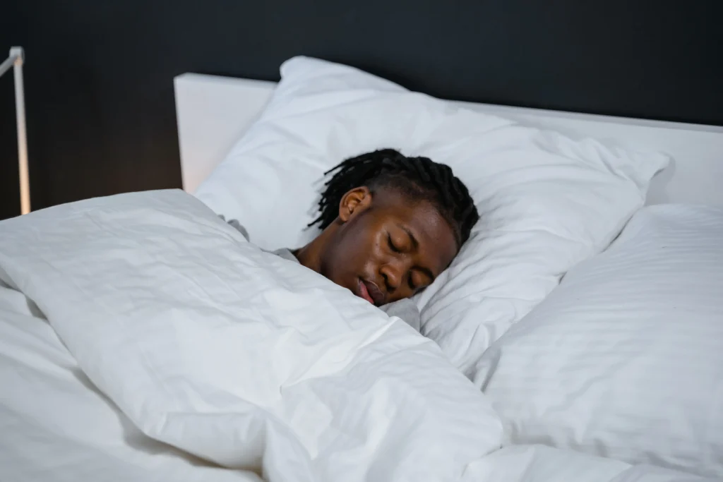 Person som sover i en säng med vita sängkläder – mäta sömn
