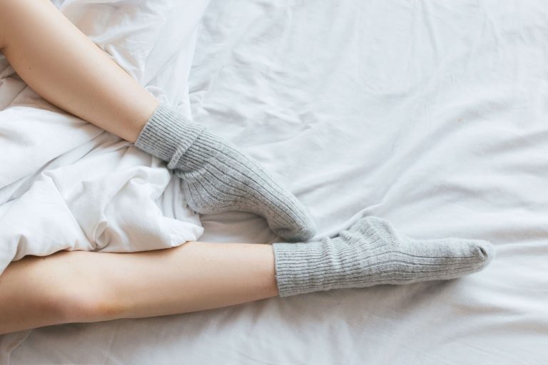 person som sover med strumpor i sängen