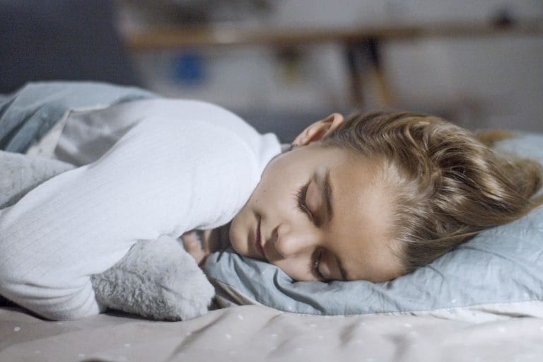 Barn som sover djupt med kinden mot kudden